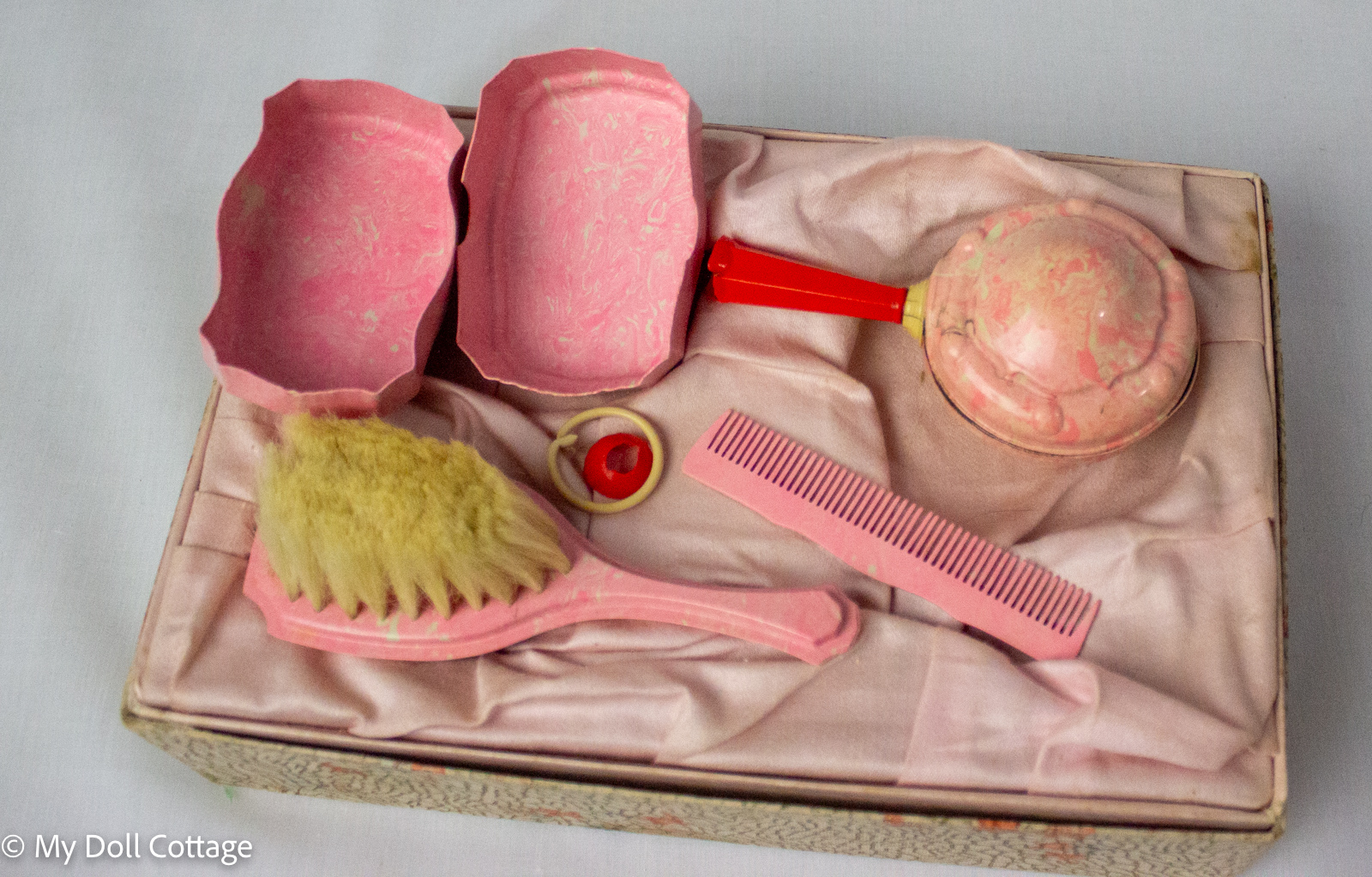 Vanity set opened to display the brush bristles, comb, powder box and baby rattle.