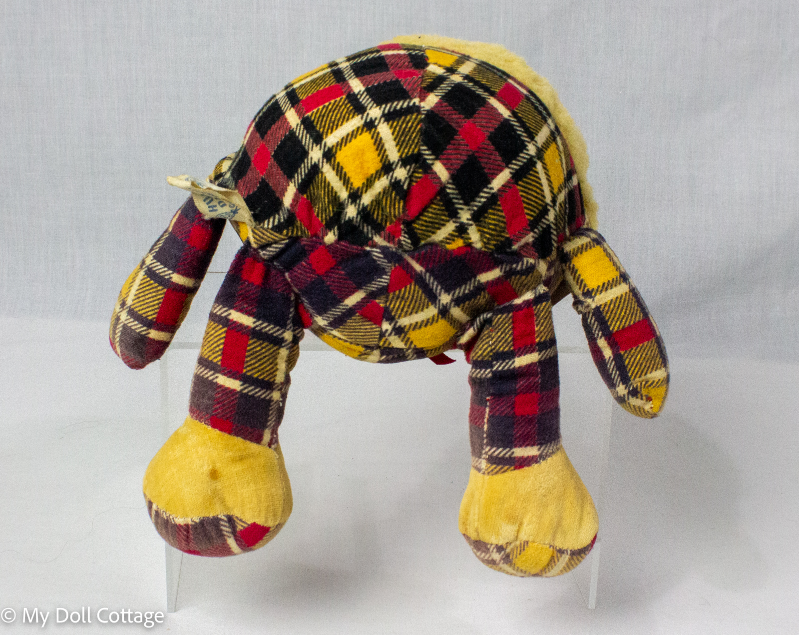 Rear view of the 1955 Knickerbocker Humpty Dumpty stuffed toy showing its rounded tartan fabric body, soft arms and legs, yellow fabric feet and surviving original tag.