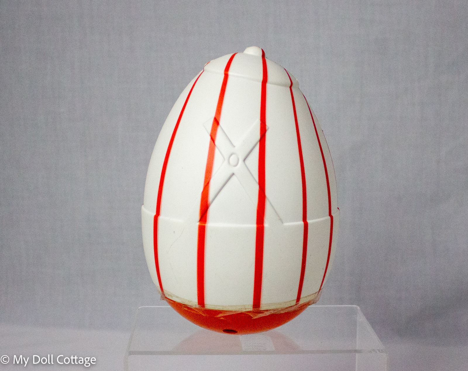 Rear view of c.1970s Humpty Dumpty roly-poly toy showing orange-red vertical stripes, moulded plastic detail, central seam and weighted rounded base.
