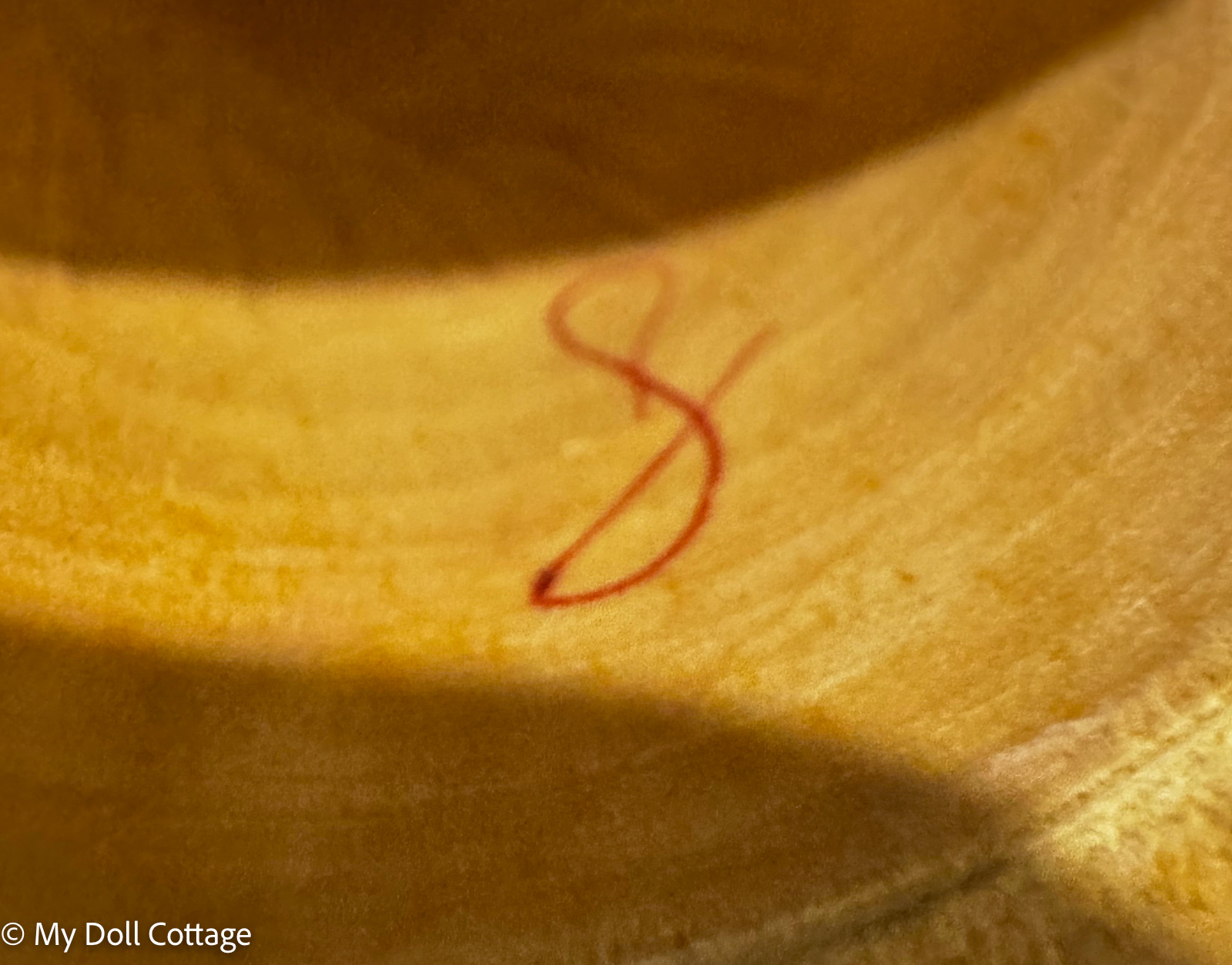 Close-up of an unidentified red painted symbol or artist's mark inside a vintage wooden nesting doll.
