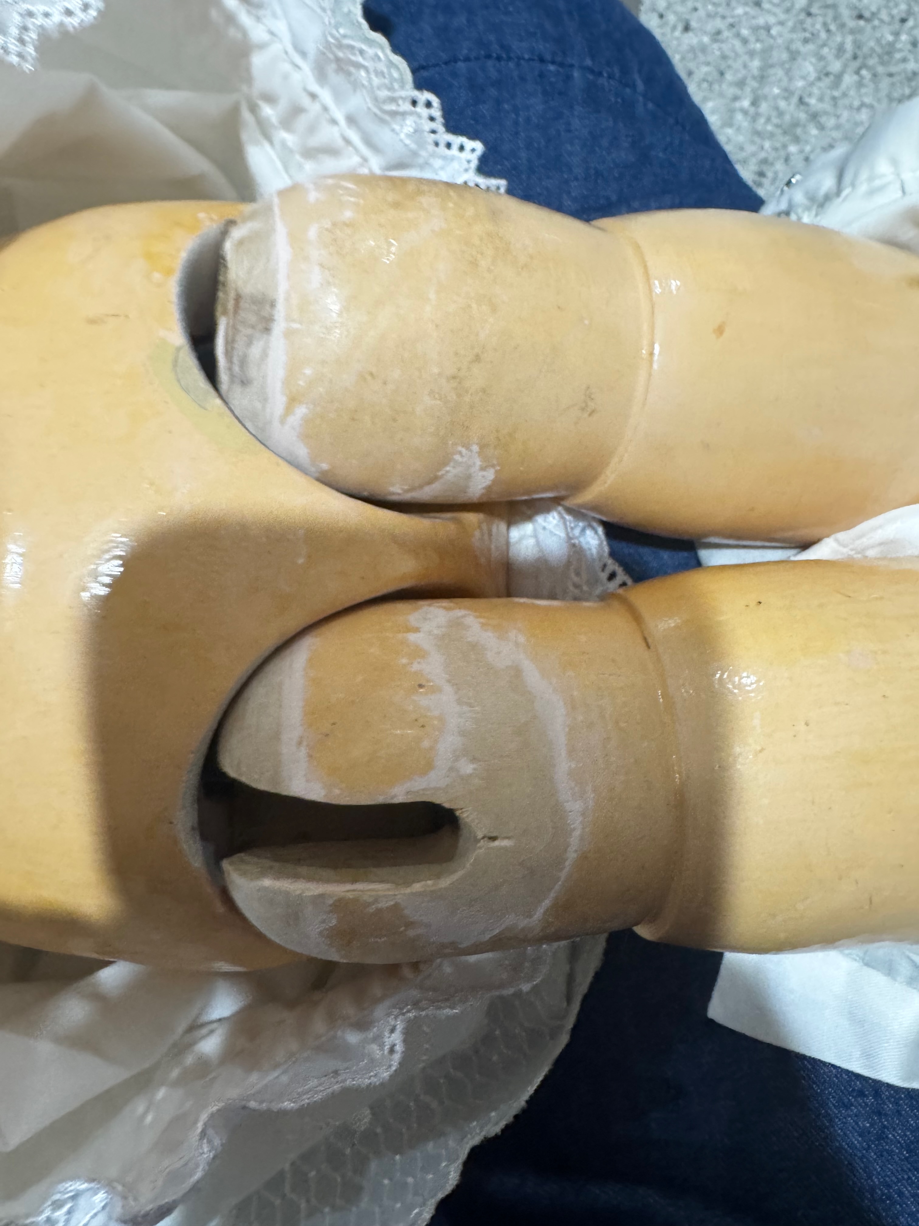 Close-up of the large Armand Marseille doll's fully jointed composition legs showing age-related wear and deterioration around the knee joints