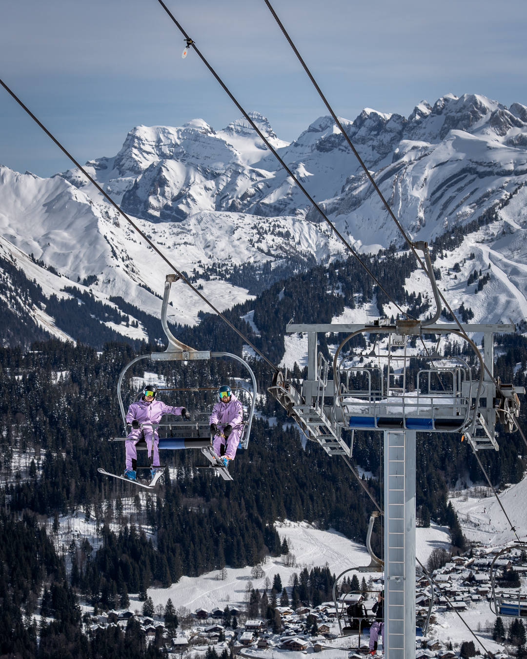 Two ski instructors riding a chairlift above Morzine with panoramic views of the Portes du Soleil.