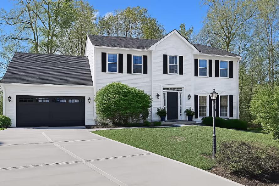 Two-story white suburban house with black shutters, black front door, attached garage, and well-maintained lawn under a clear blue sky.