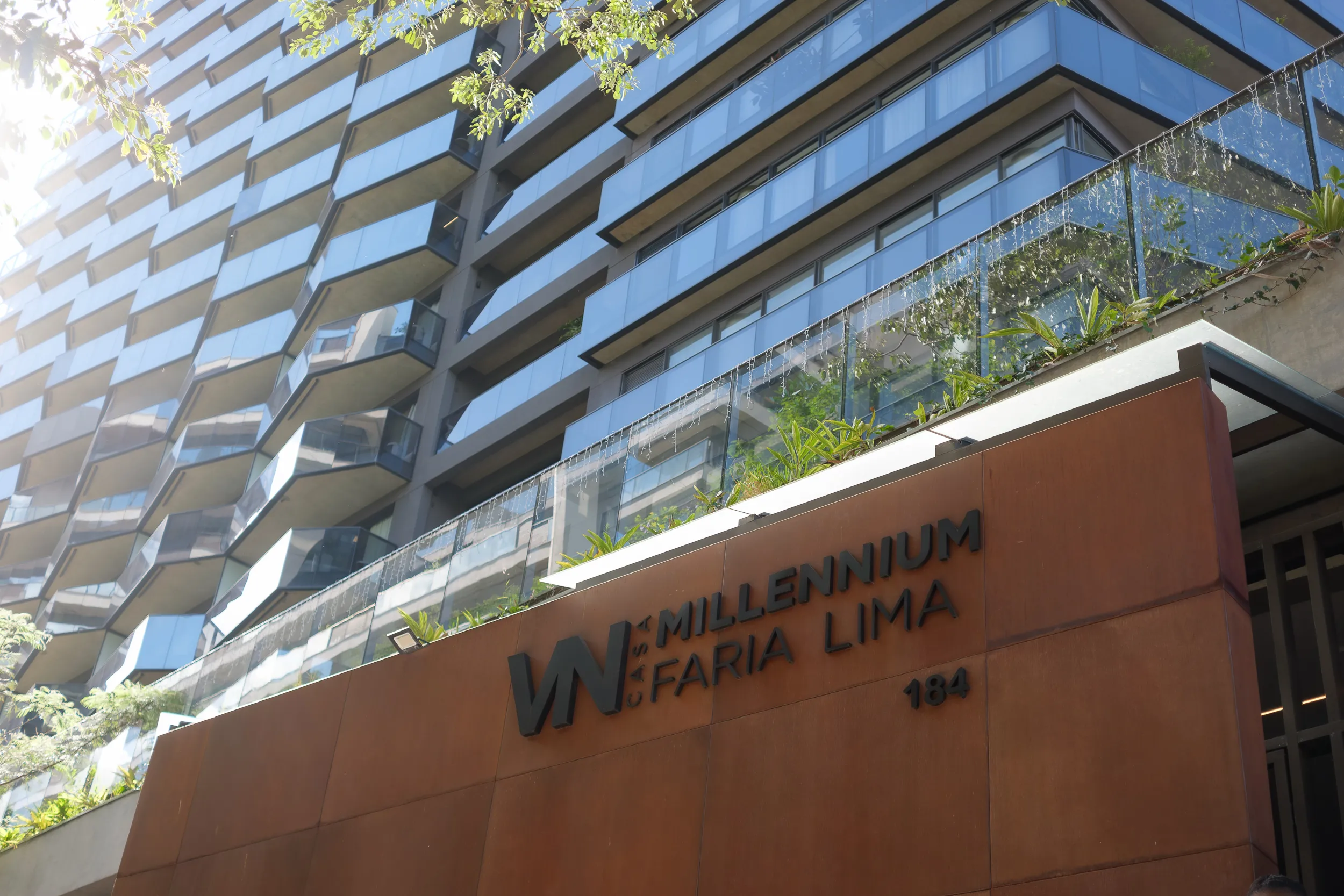Exterior of a modern multi-story building with balconies and a sign reading 'Millennium Faria Lima'.