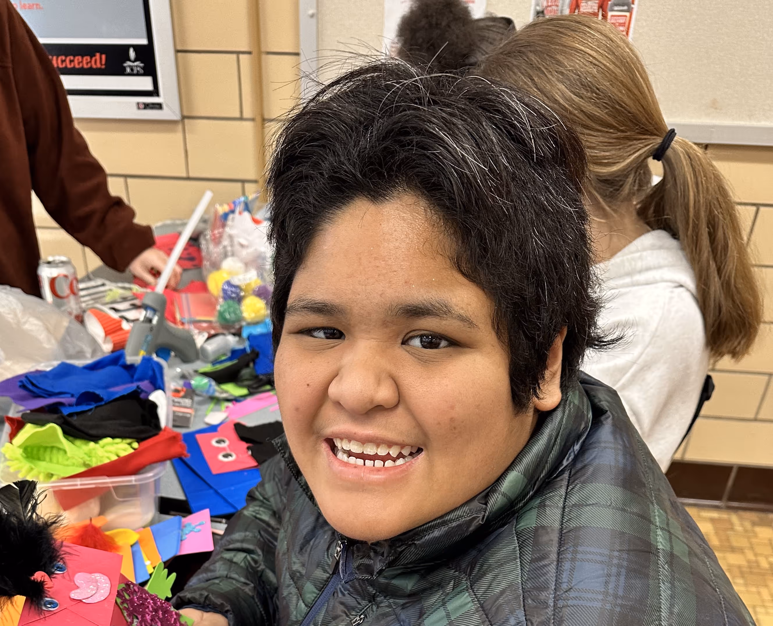 Smiling student creates colorful puppets during Actors Theatre of Louisville arts workshop.