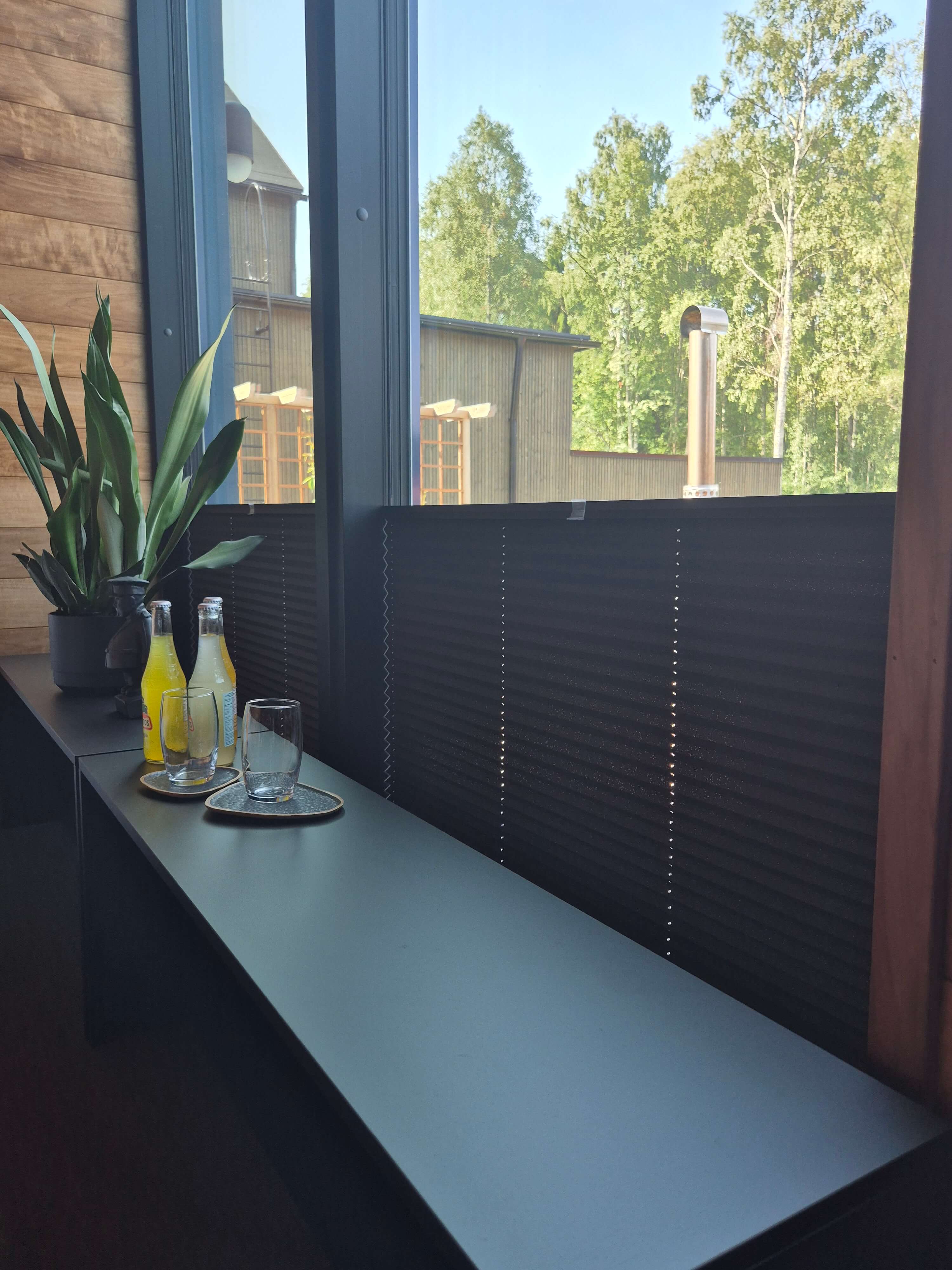 Parveke, jossa moderni musta taso, kasvi, kaksi limonadipulloa ja kaksi tyhjää juomalasia.