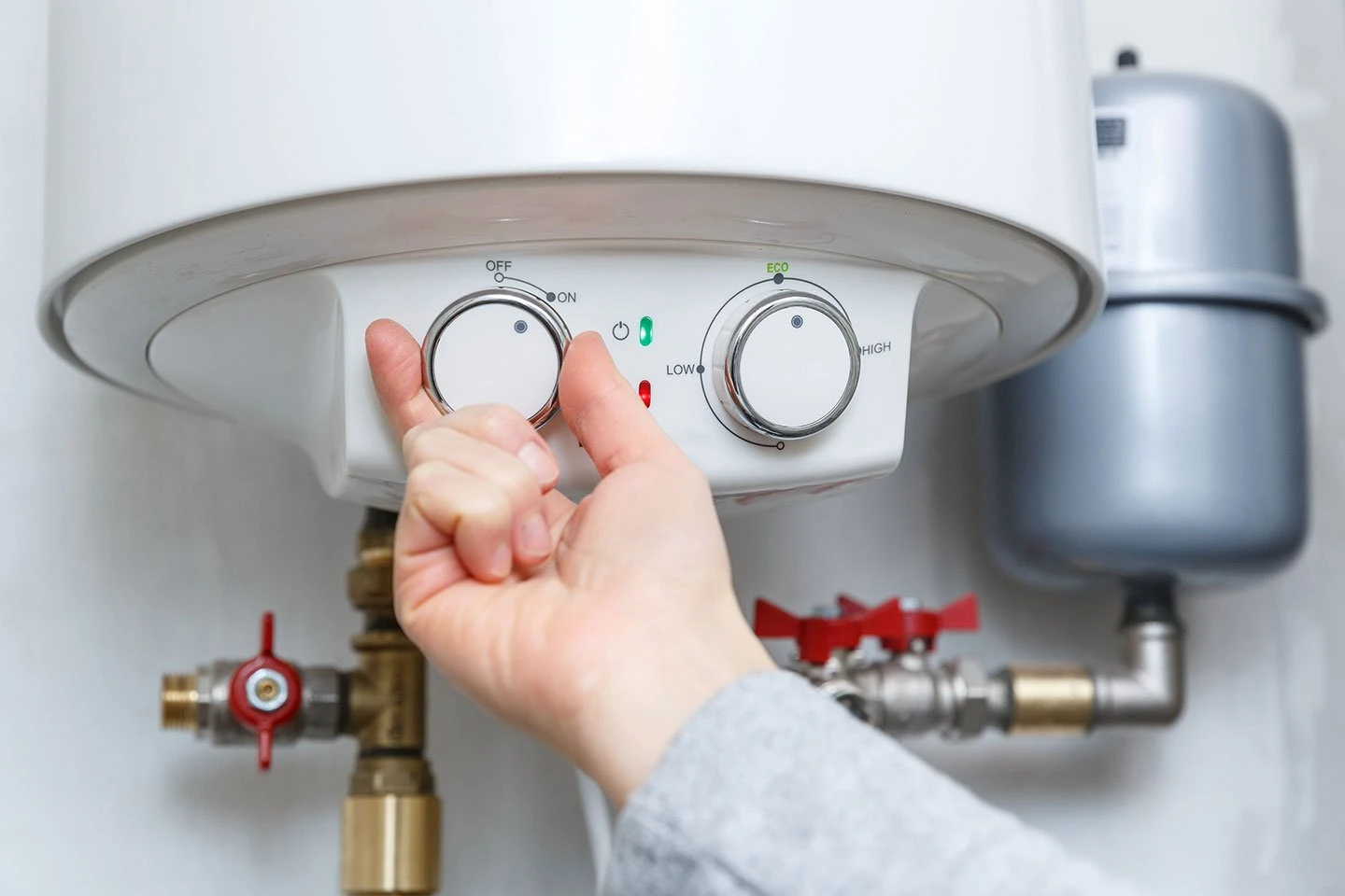 A hand turning on a water heater.