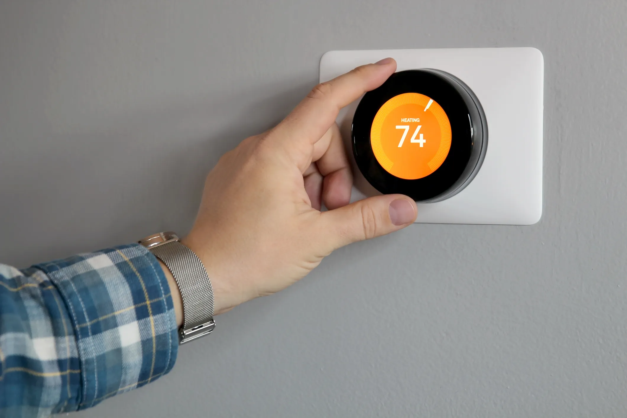 technician inspecting a smart thermostat in a modern Charleston living room