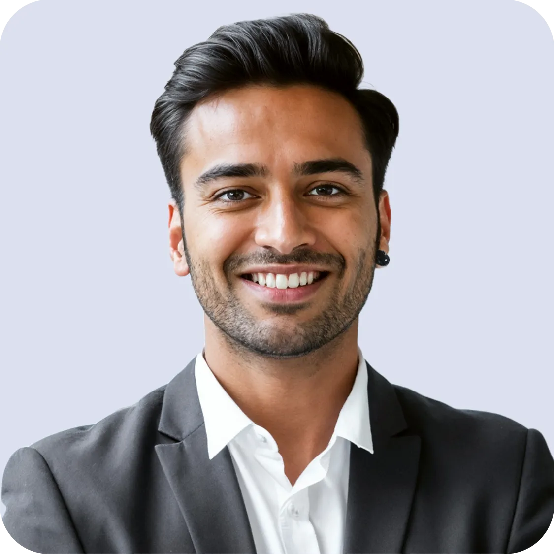 Smiling man with dark hair and beard wearing a dark blazer and white shirt against a light background.