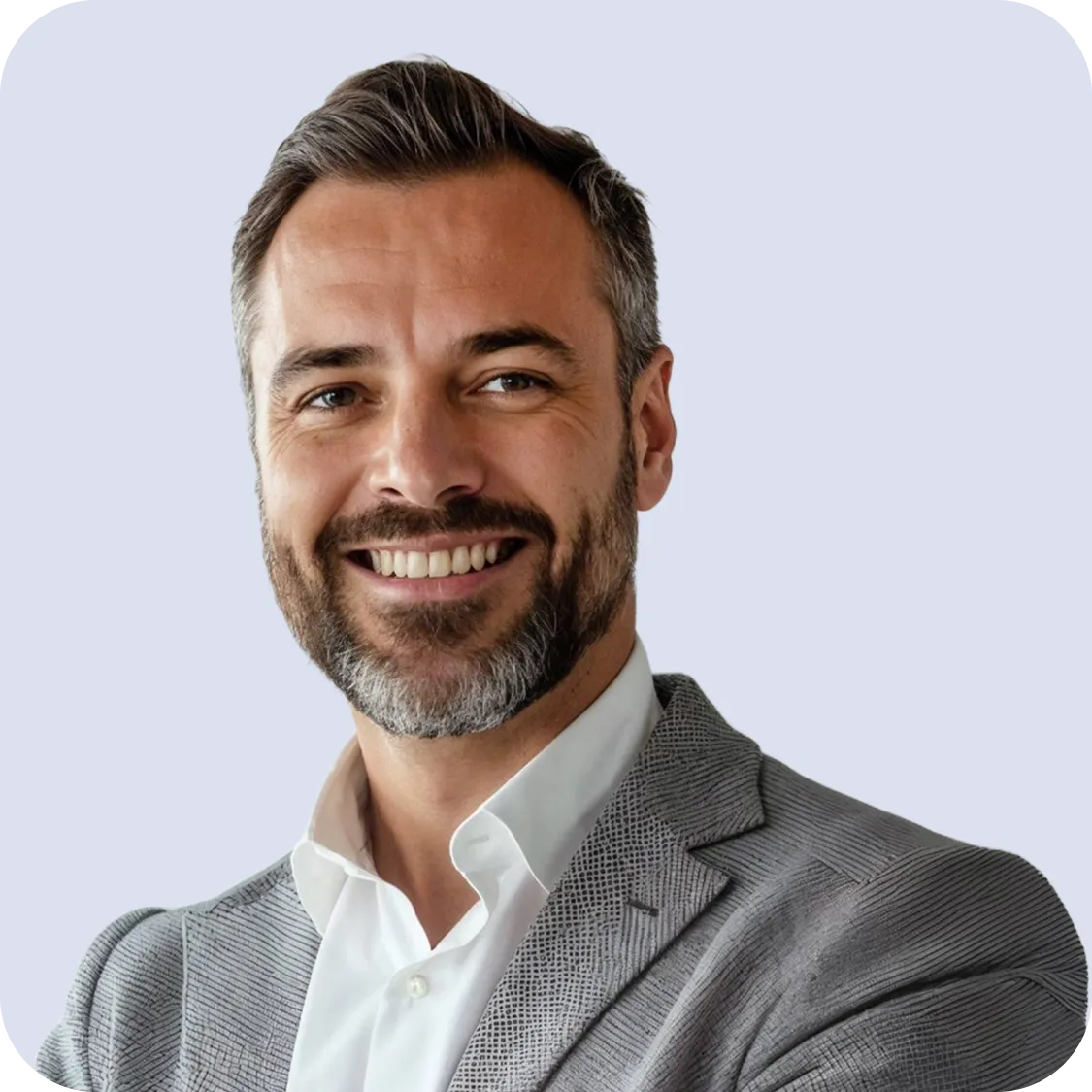 Smiling middle-aged man with short grayish hair and beard wearing a white shirt and gray blazer.