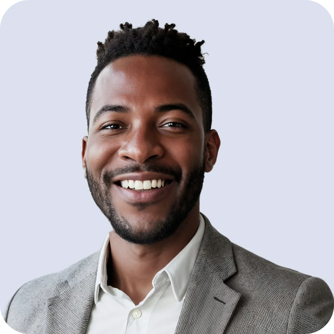 Smiling man with short curly hair wearing a gray suit jacket and white shirt against a light background.