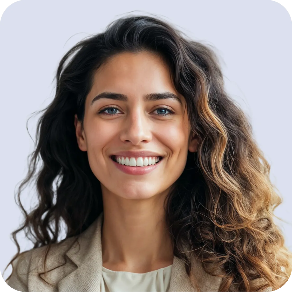 Smiling woman with long curly hair wearing a beige blazer and light-colored top against a light background.