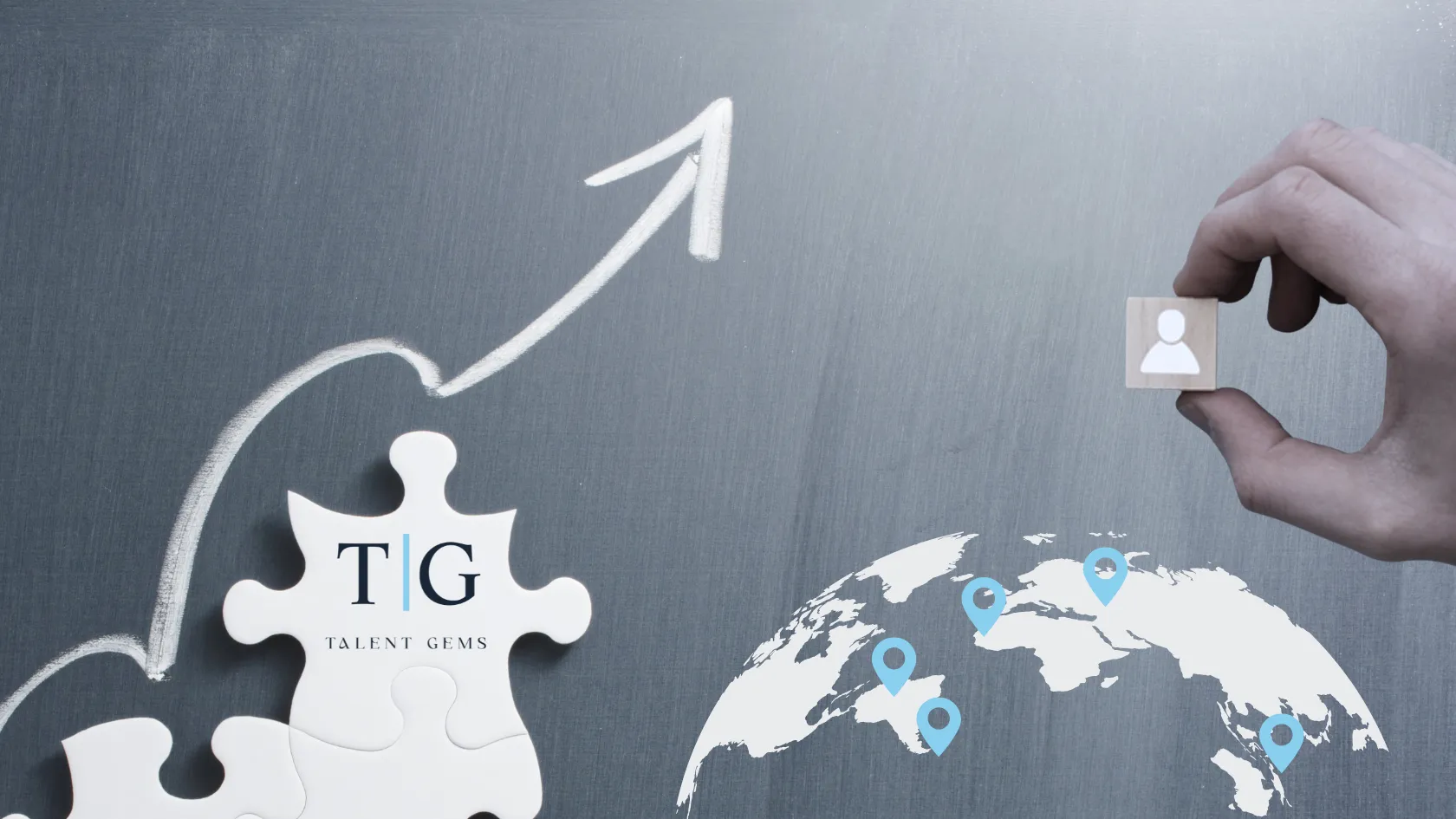 Hand holding a wooden block with a person icon near a puzzle piece labeled TG Talent Gems and a world map with blue location markers and an upward arrow on a chalkboard.