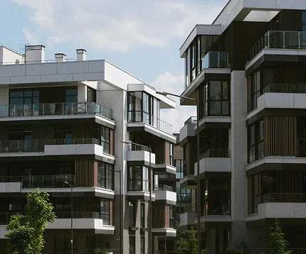 Modern multi-story residential buildings with balconies under a partly cloudy sky.