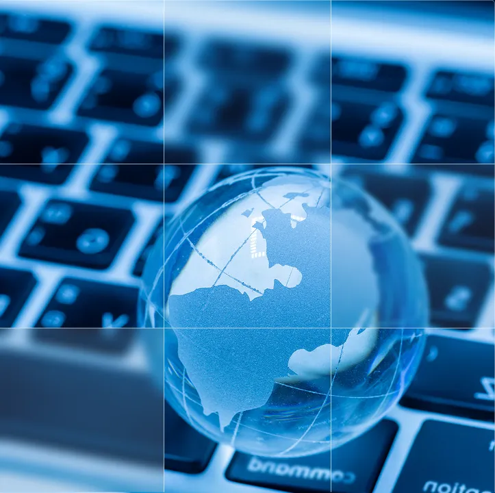 Transparent globe with continents resting on a laptop keyboard in blue lighting.