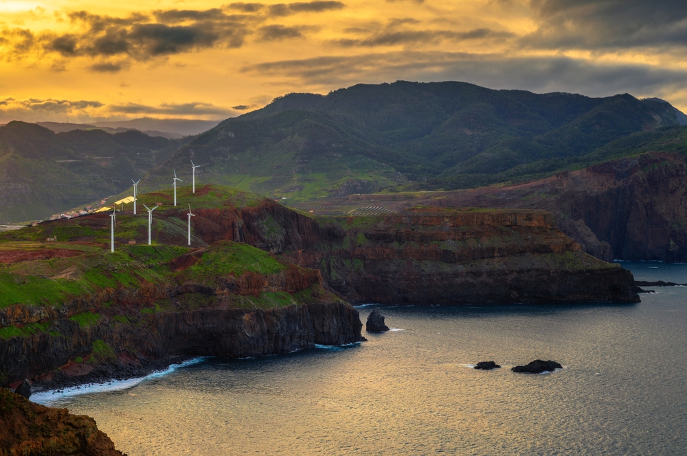 Sun setting on mountainous region with wind turbines