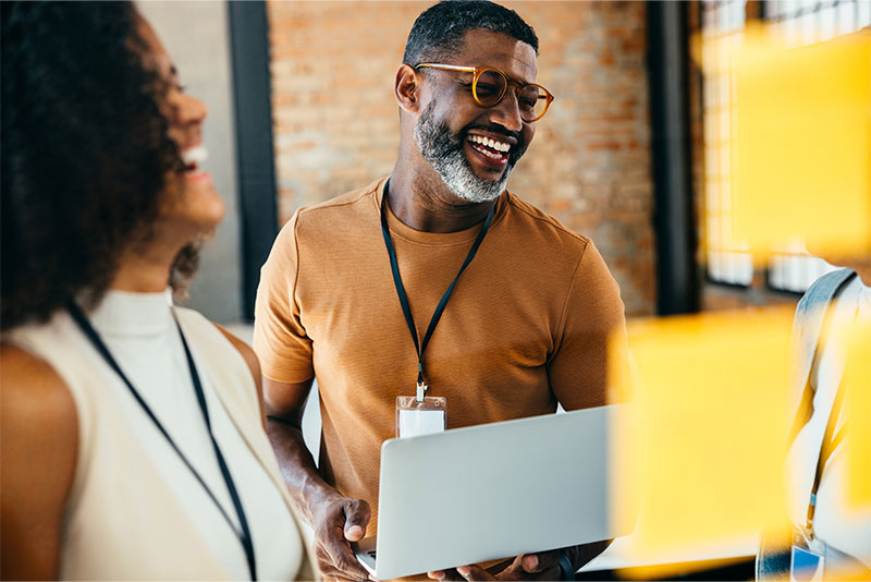 Business professionals laughing around a laptop