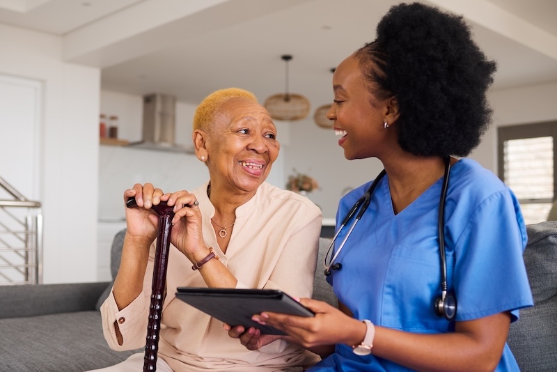 Woman with cane talking to a nurse on an ipad