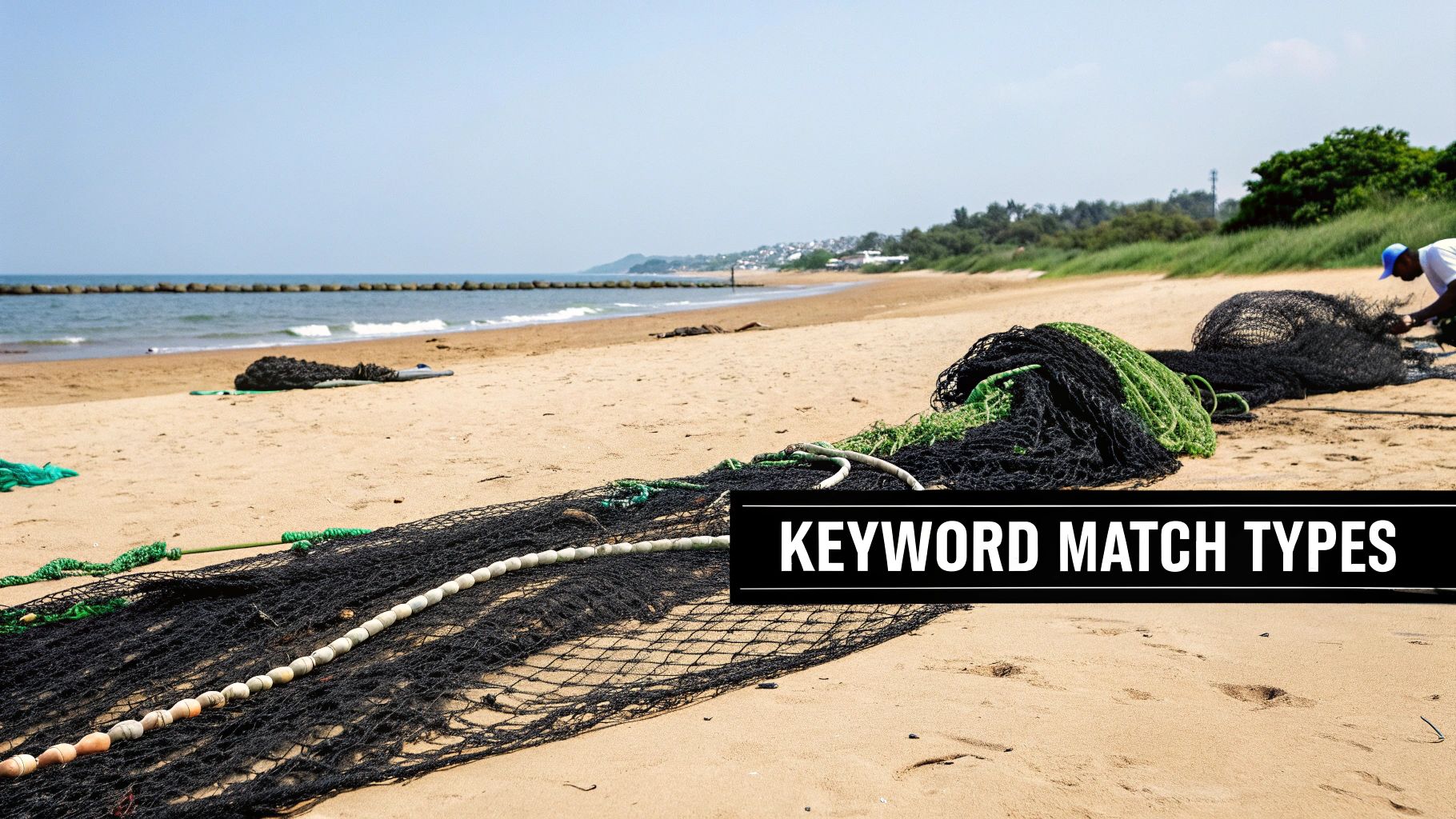 A sandy beach with black and green fishing nets, buoys, and ropes, with a fisherman in the background.