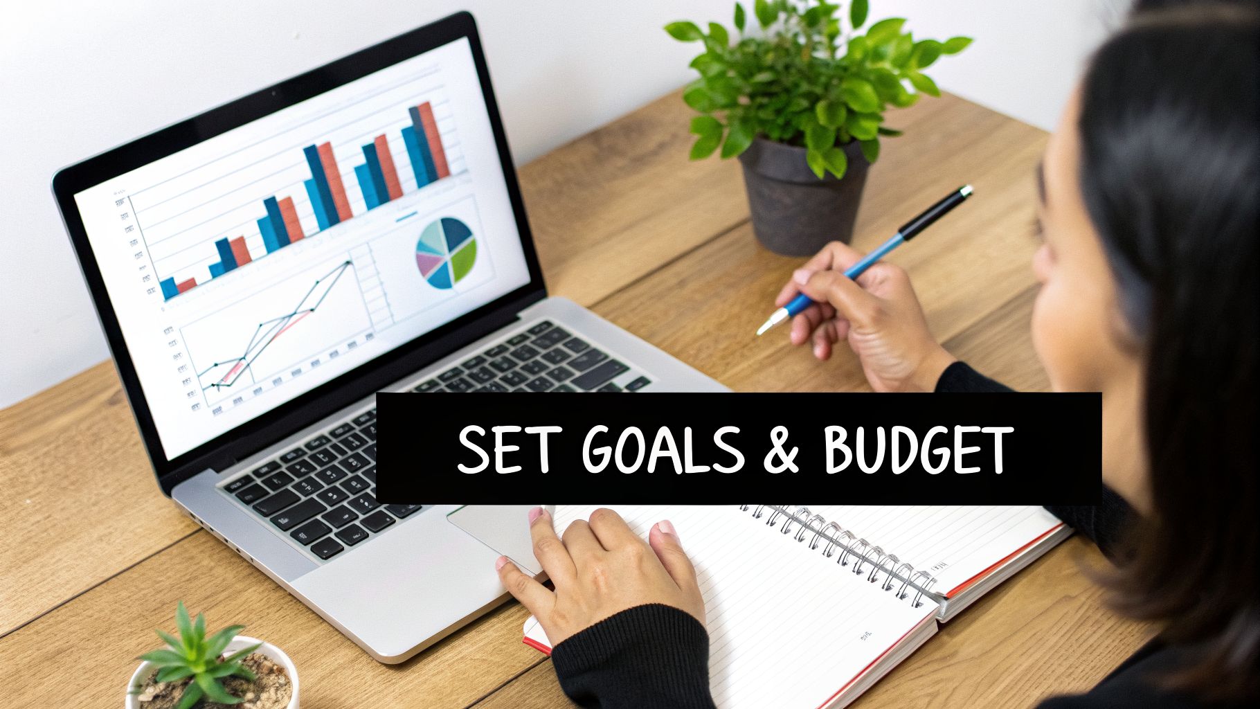 A person reviews financial charts on a laptop while writing in a notebook, setting goals and budget.