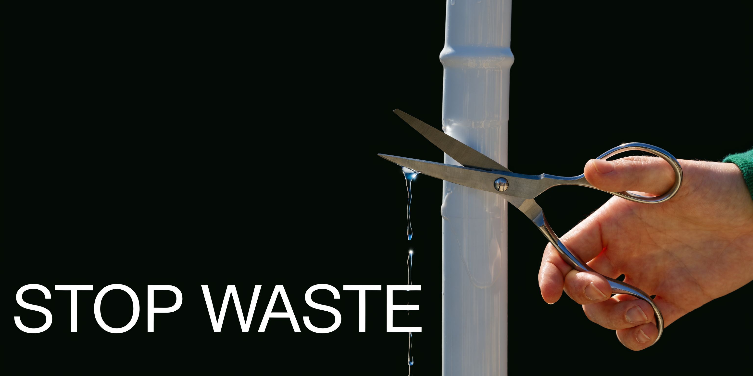 A hand holding scissors cutting through a leaking white pipe against a solid black background.