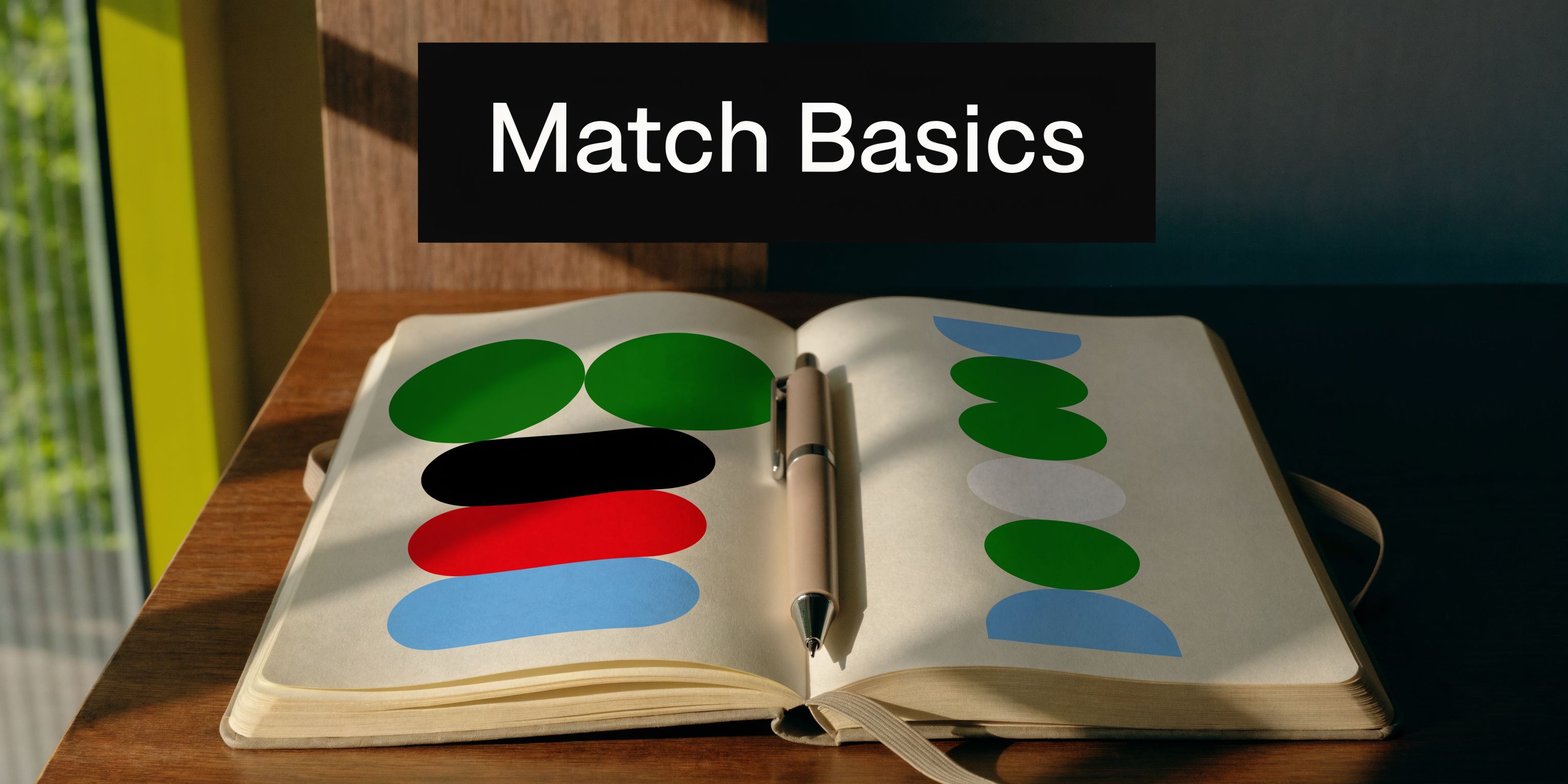 An open journal lies on a wooden desk with colorful abstract shapes and a metal pen inside.