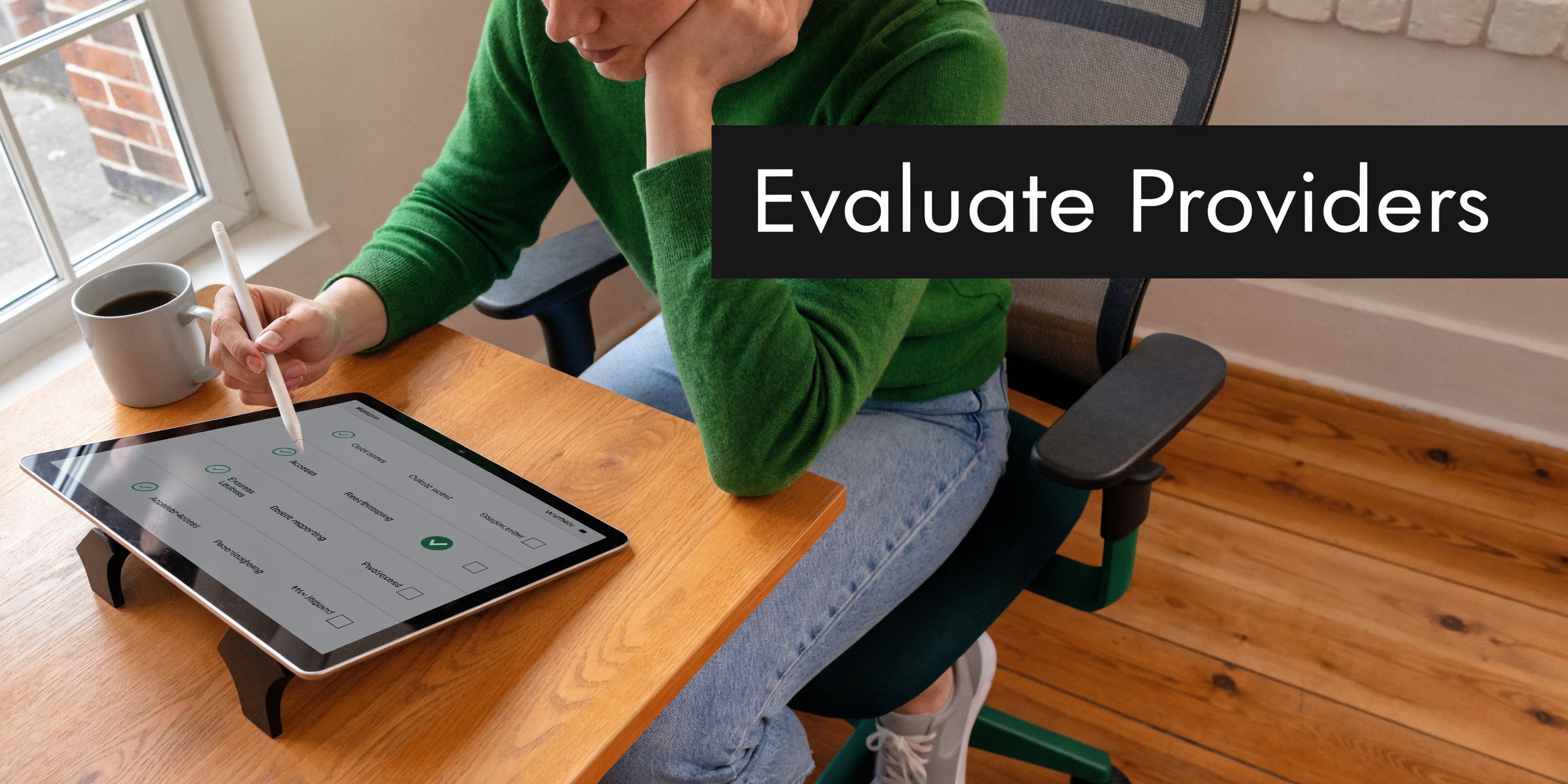 A person sitting at a desk and evaluating provider information on a tablet computer with a stylus.