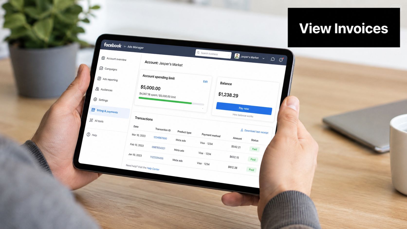 A person holding a tablet showing the Facebook Ads Manager billing and payments dashboard interface.