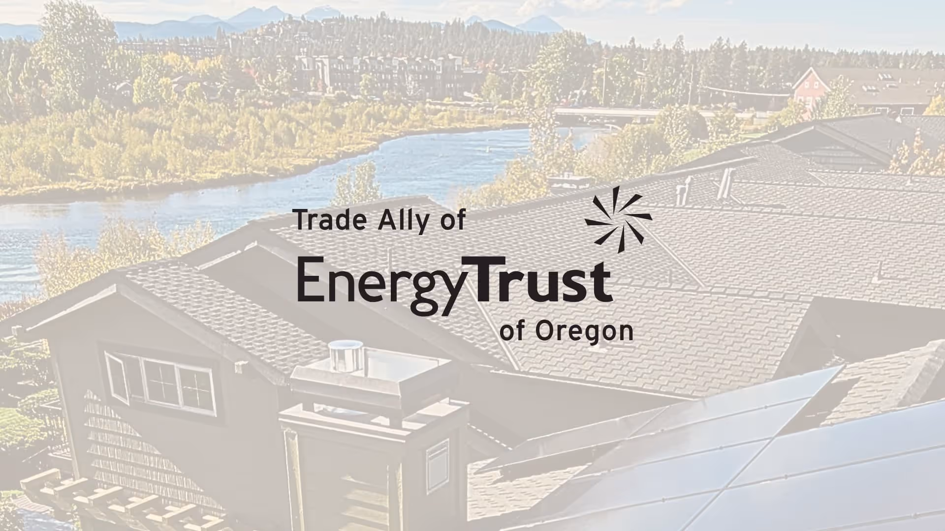Rooftop with solar panels overlooking trees and a river with the text 'Trade Ally of Energy Trust of Oregon'.