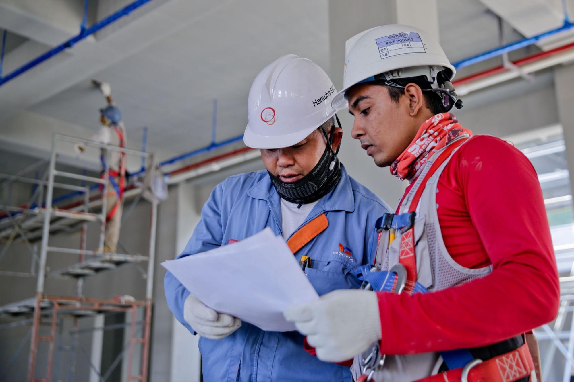Workers reviewing workplace safety documents at a job site as part of an ISO 45001 occupational health and safety management process.
