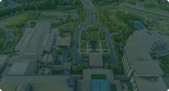 Aerial view of a large building complex surrounded by greenery and roads.