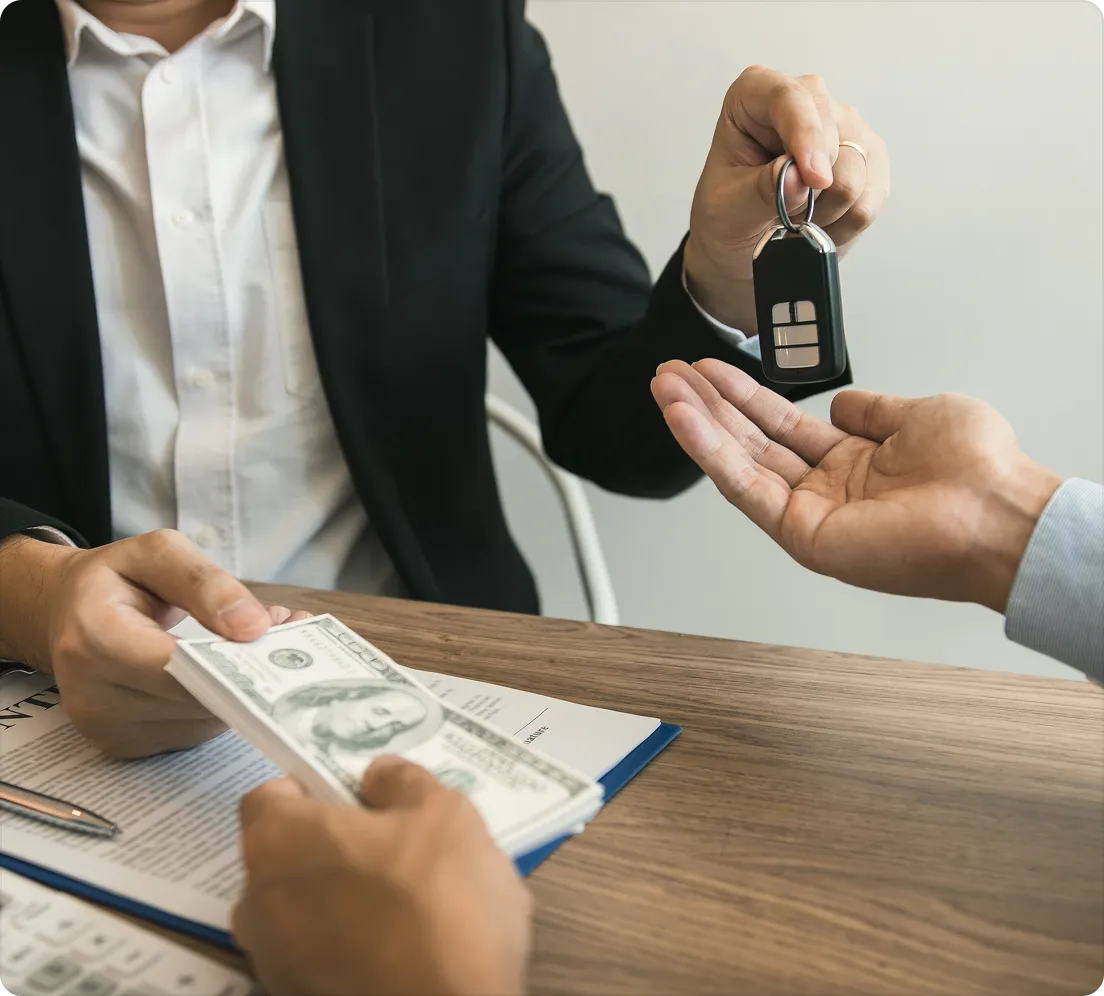 House keys handed across a desk while a stack of cash is passed over a contract