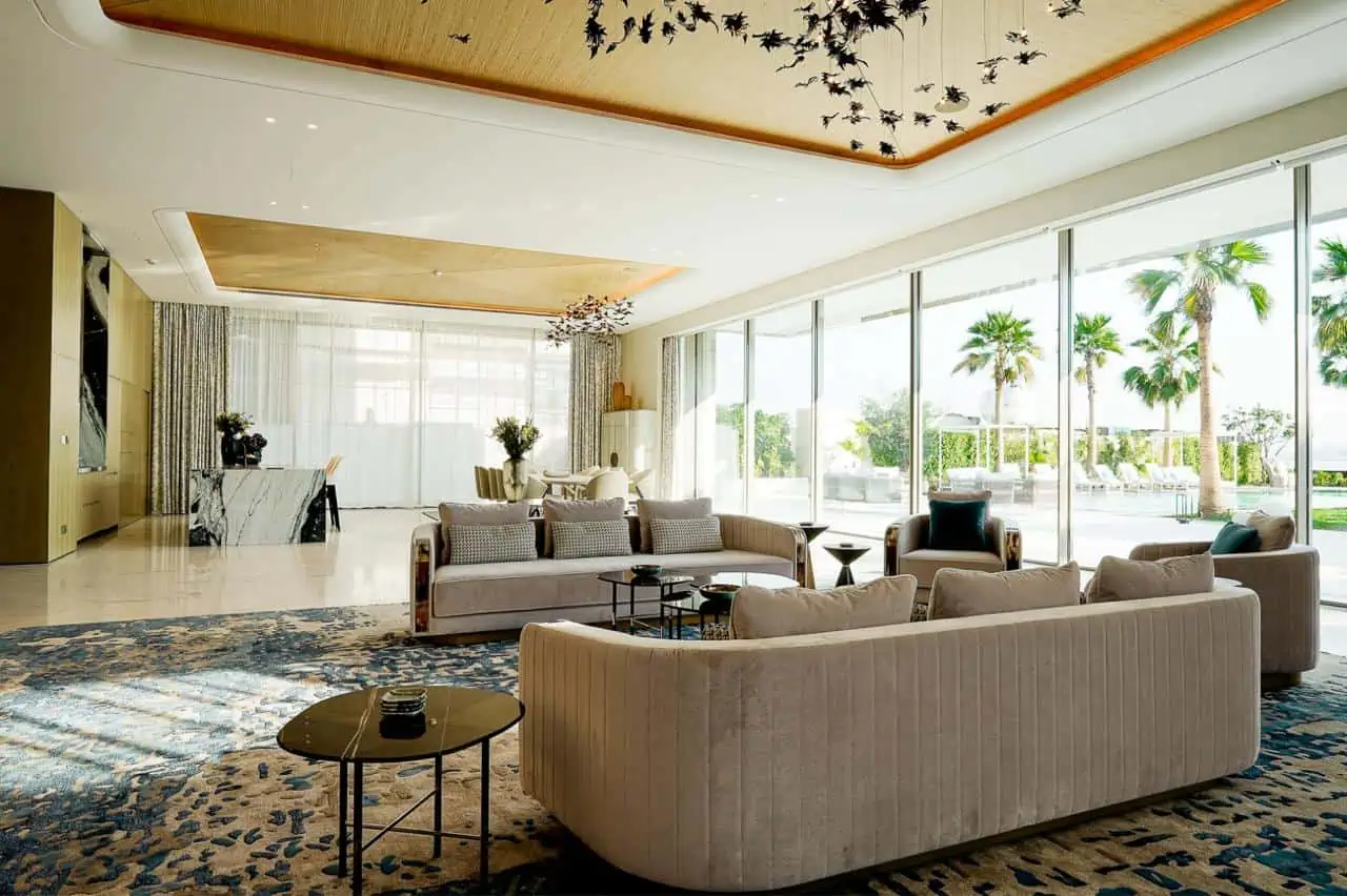 A spacious living room featuring a large glass wall and a comfortable couch, inviting natural light and relaxation.