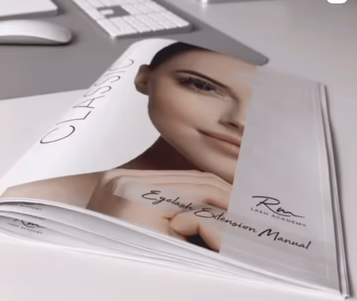 RM Lash Academy’s printed Classic Eyelash Extension Manual on a desk.