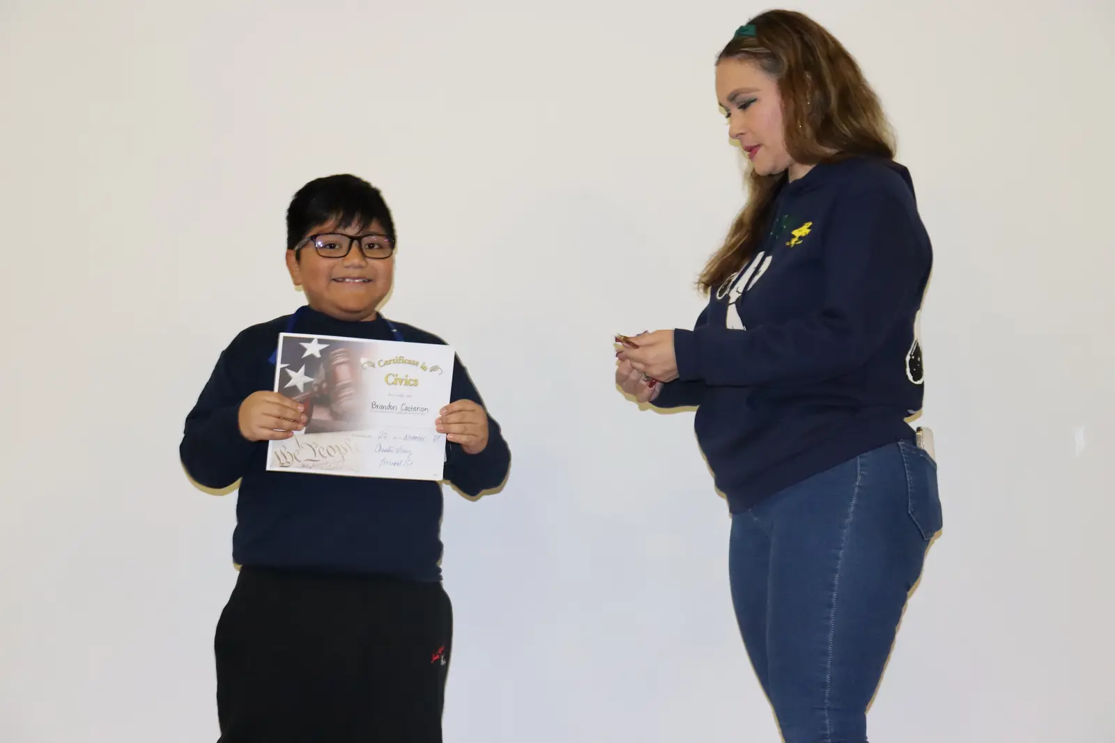 Student holding civics certificate with teacher applauding