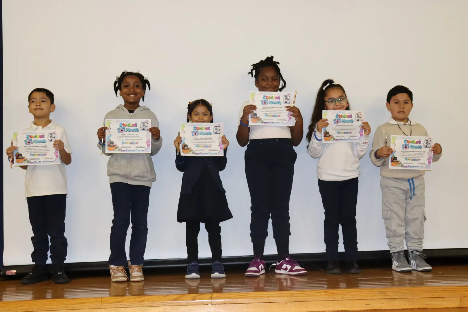 Six students holding Student of the Month certificates