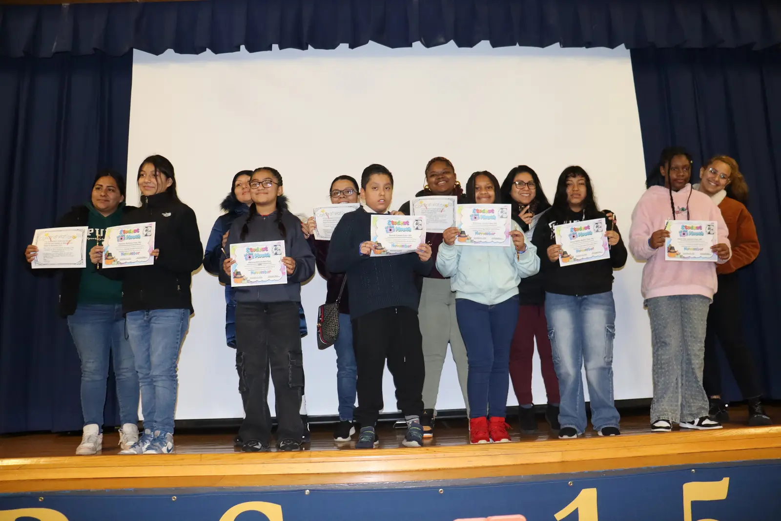 Students holding certificates on stage at award ceremony