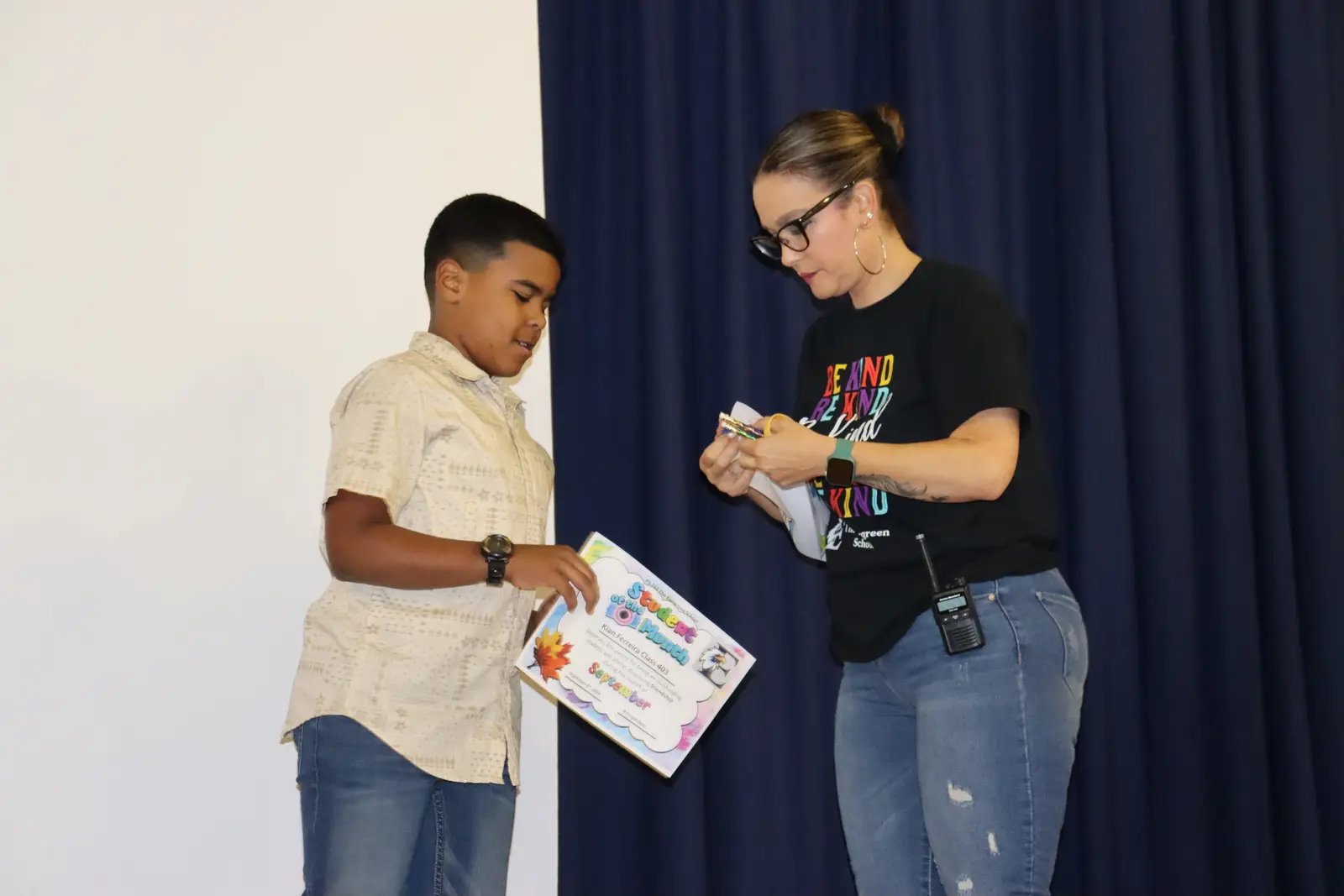 Teacher presenting certificate to student at school assembly