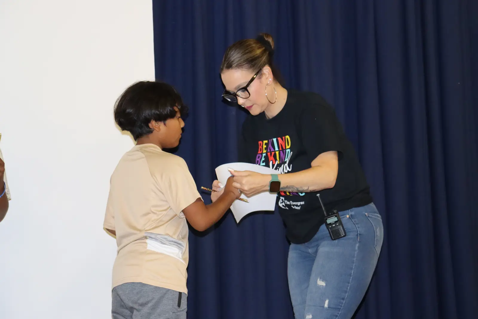 Teacher handing certificate to student at school event