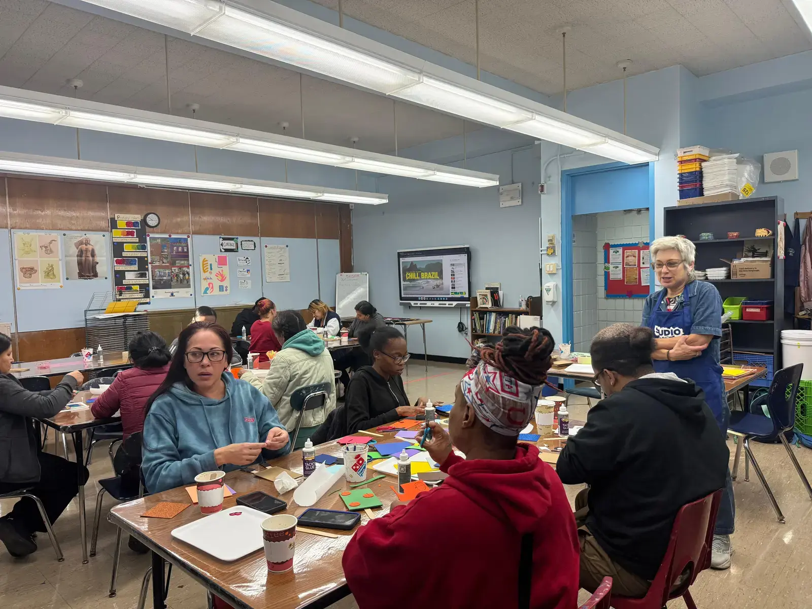 Students working on art projects with teacher in classroom