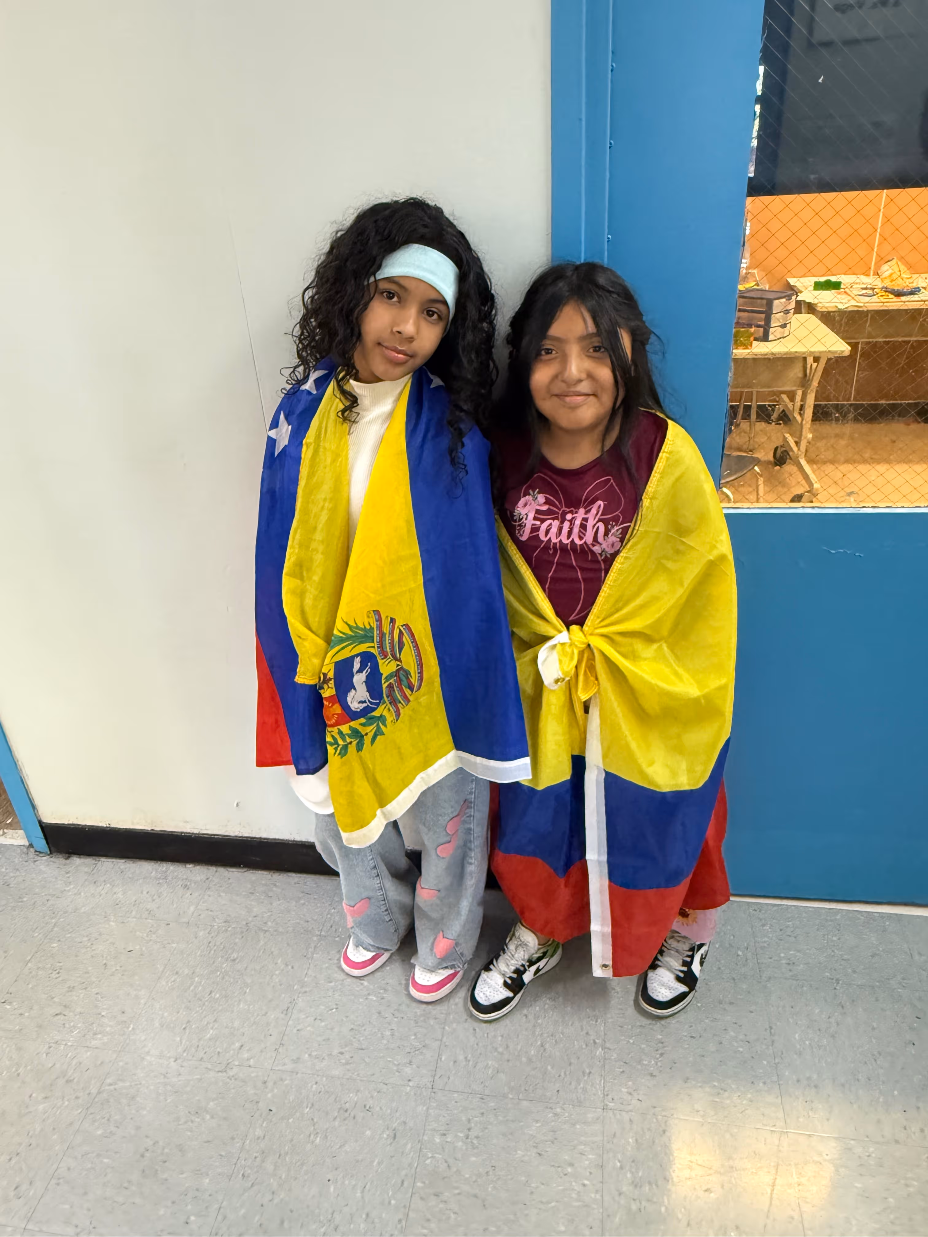 Two students wearing Venezuelan and Colombian flags at school