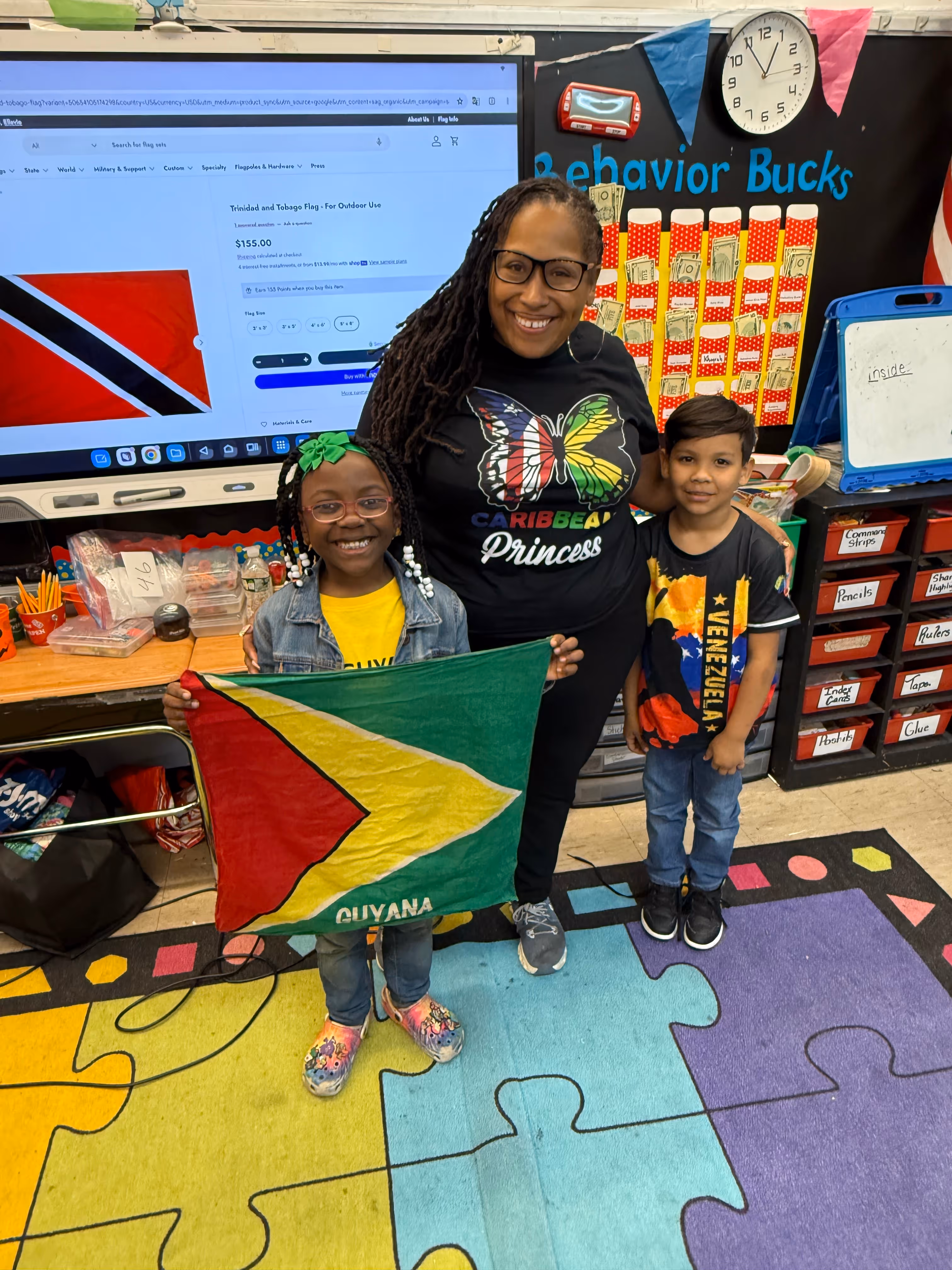 Teacher and two students displaying Guyana and Venezuela flags in classroom