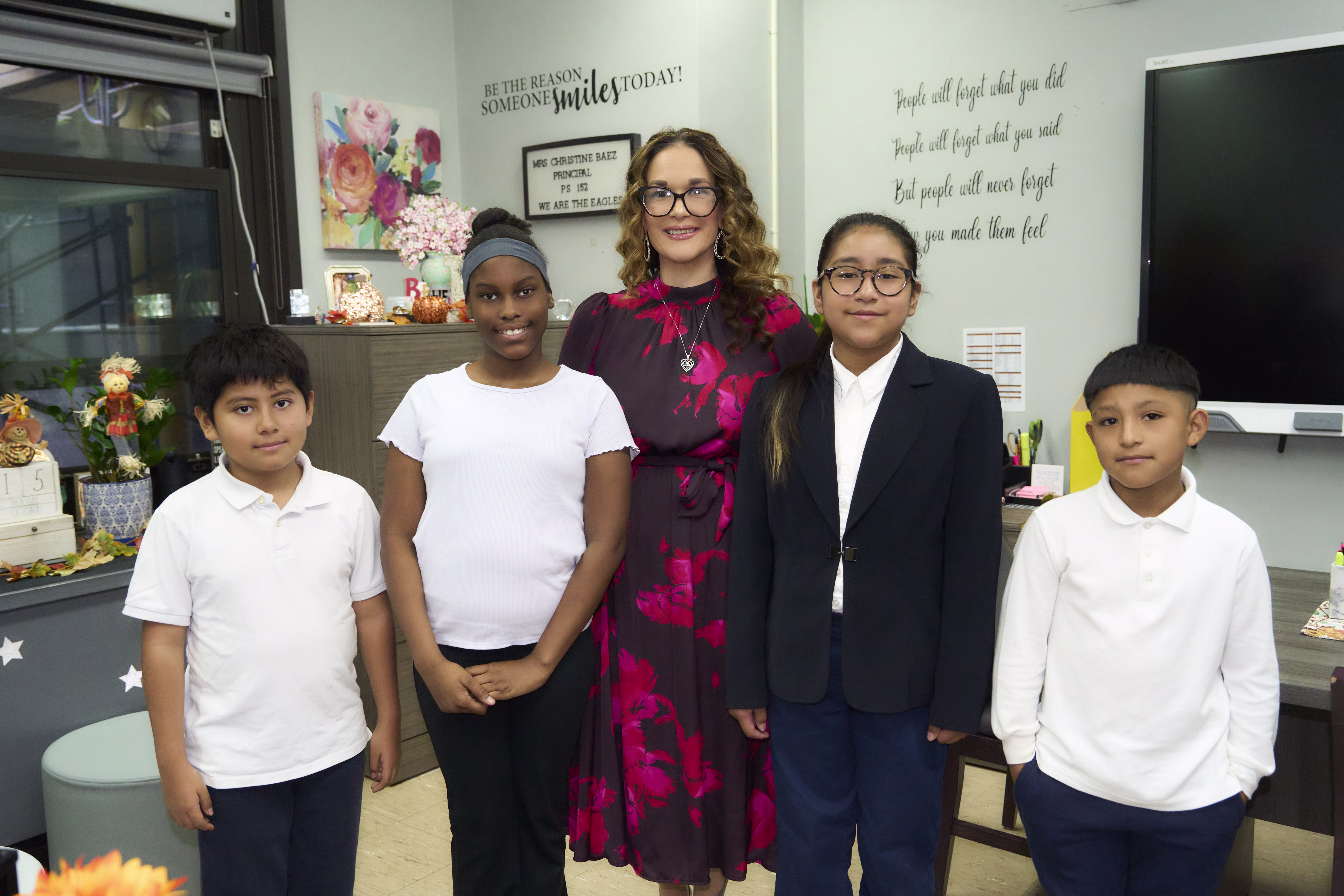 Teacher and students posing together in front of Together We SOAR display
