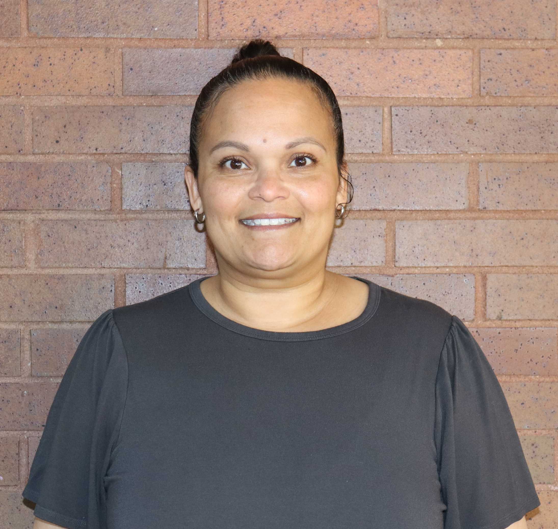 Ms. Ochoa smiling in front of a brick wall