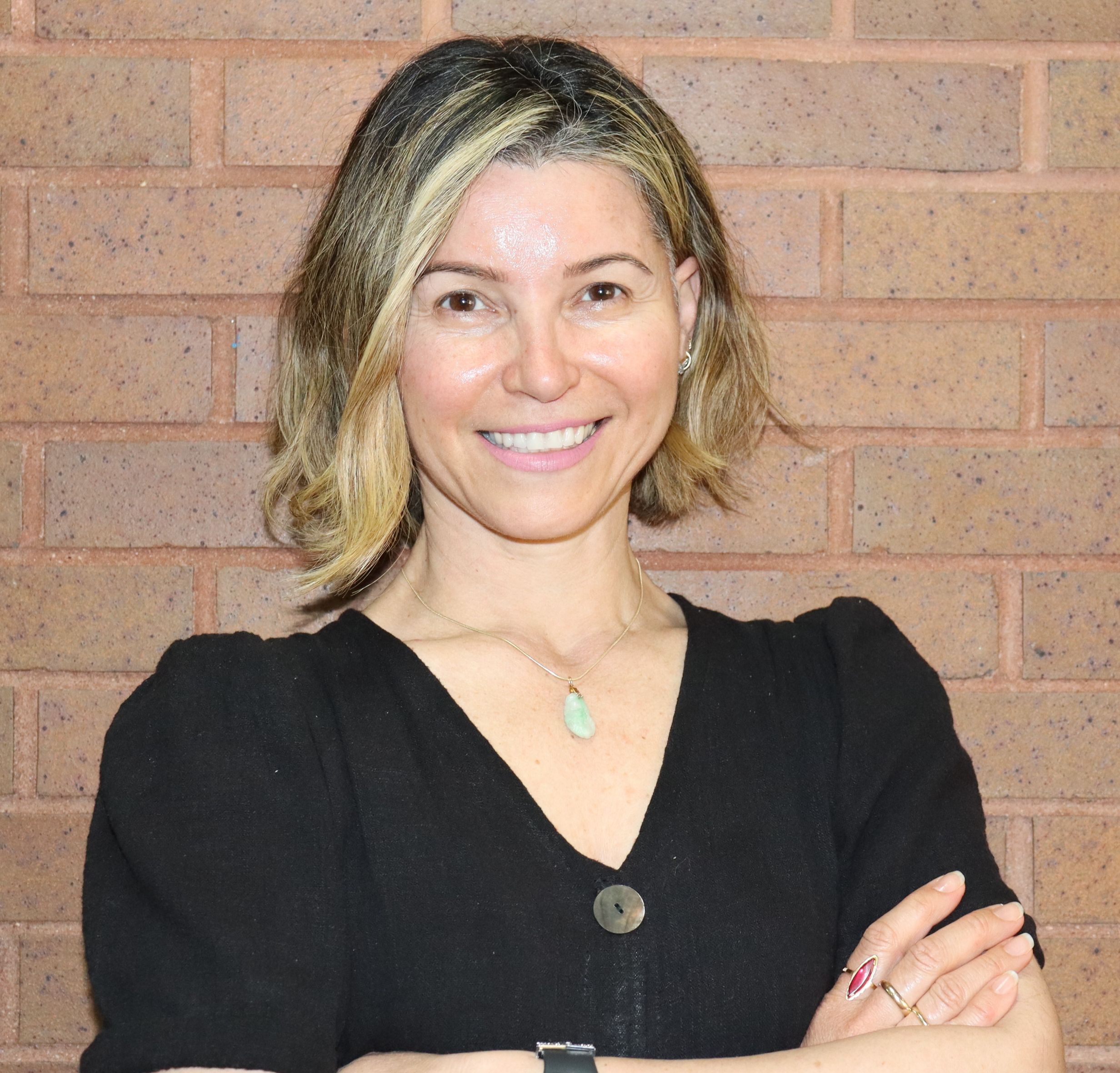 Ms K Irizarry smiling in front of a brick wall