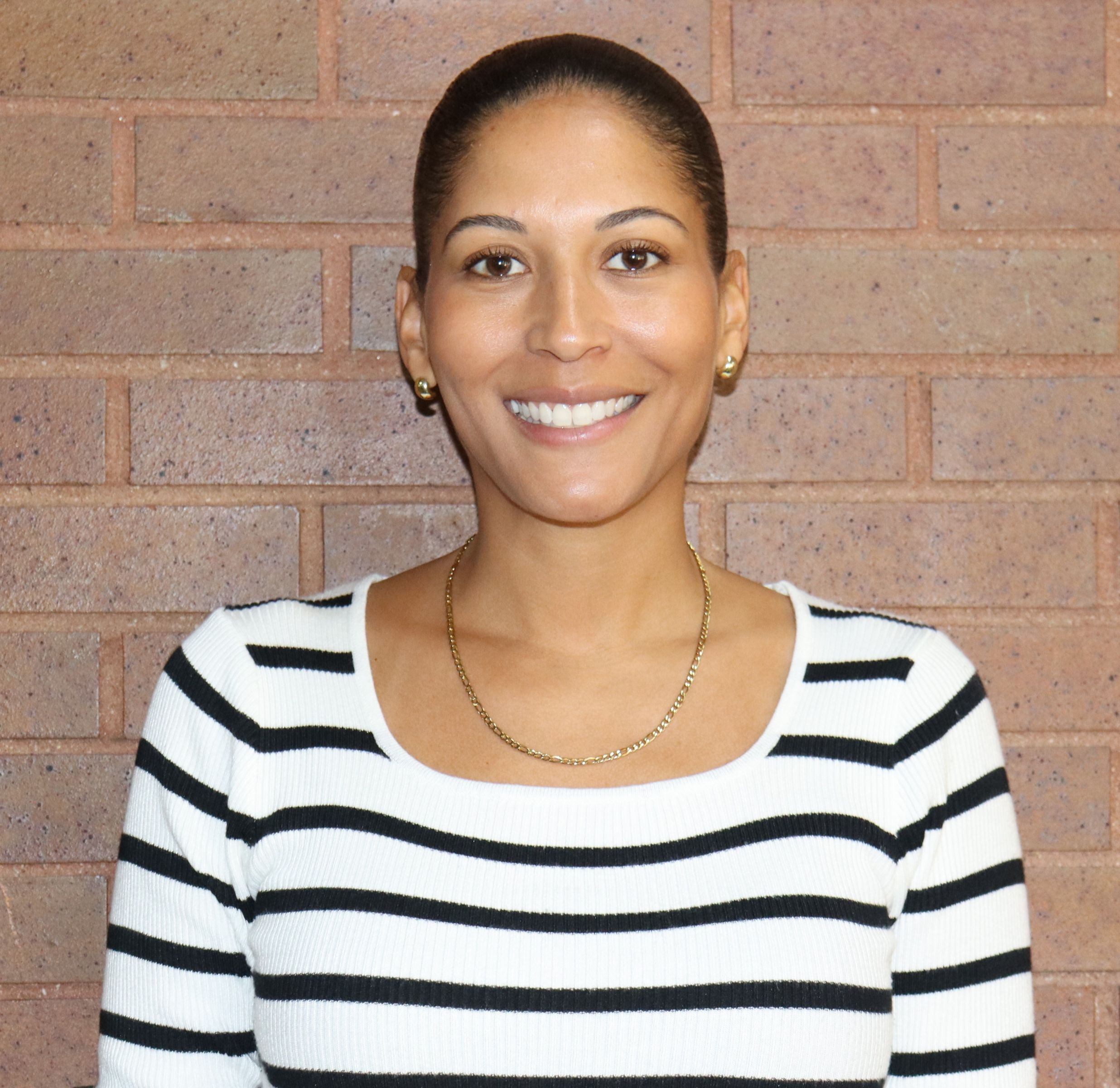 Ms. Gonzalez smiling in front of a brick wall