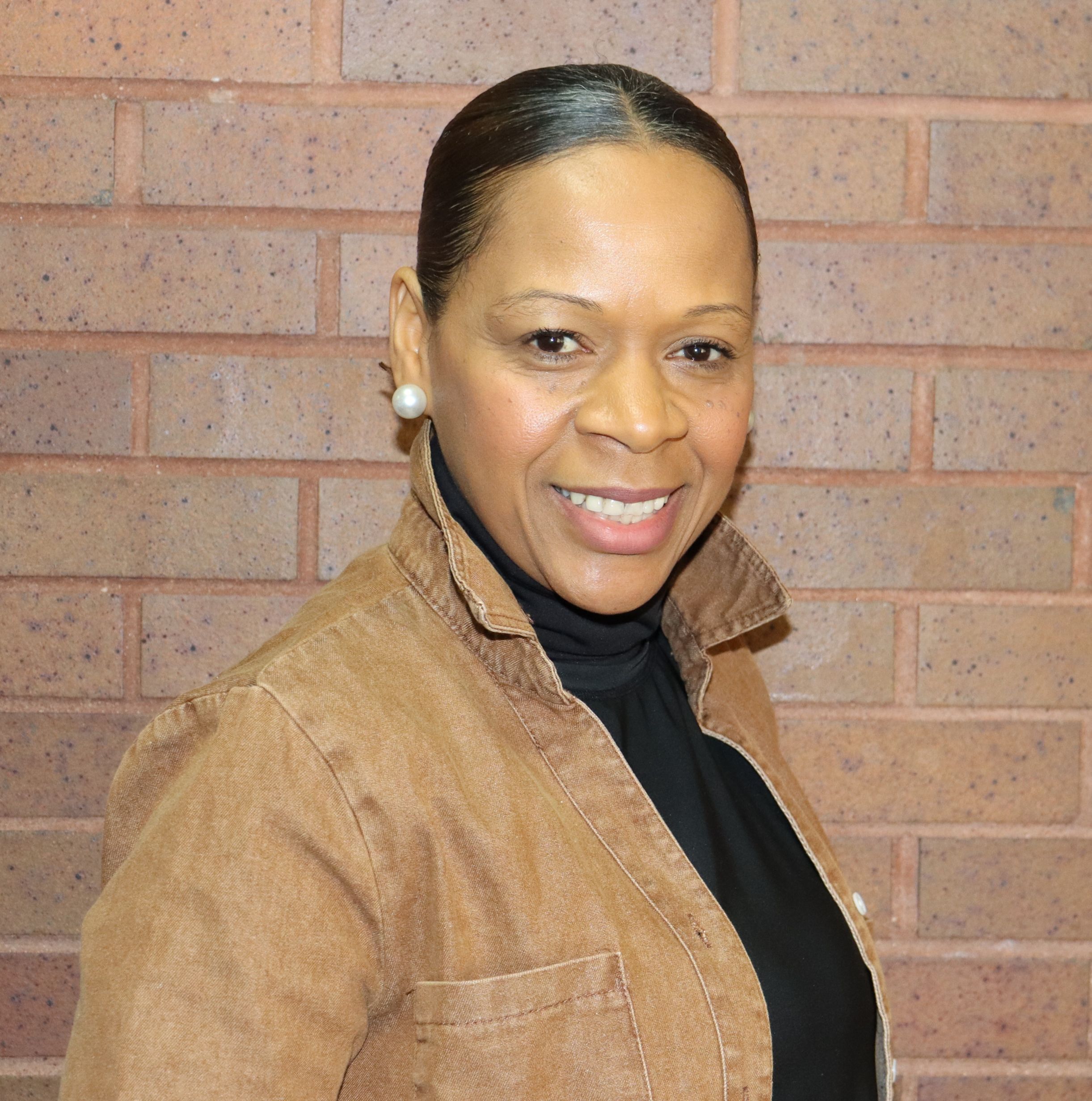 Ms. Solano smiling in front of a brick wall