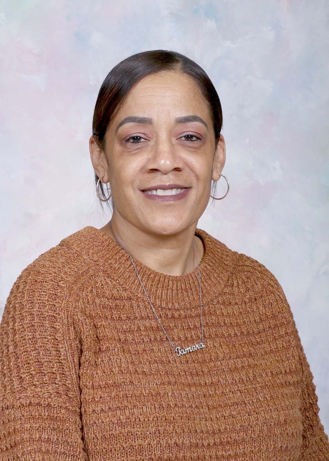 Tamara Ortiz staff portrait photo smiling in brown sweater