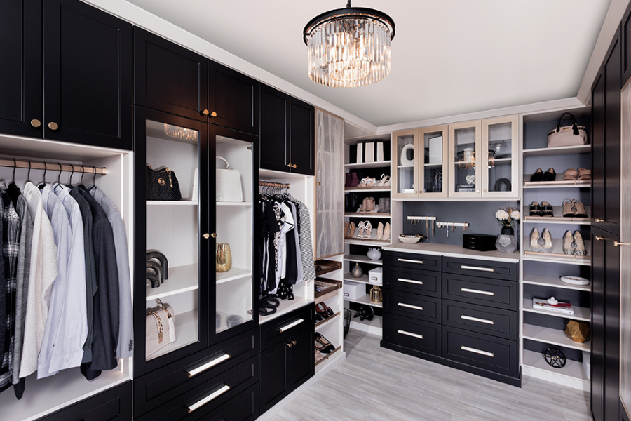 Stylish custom closet with black cabinetry, glass doors, ample drawer space, and shelves for shoes, handbags, and accessories.