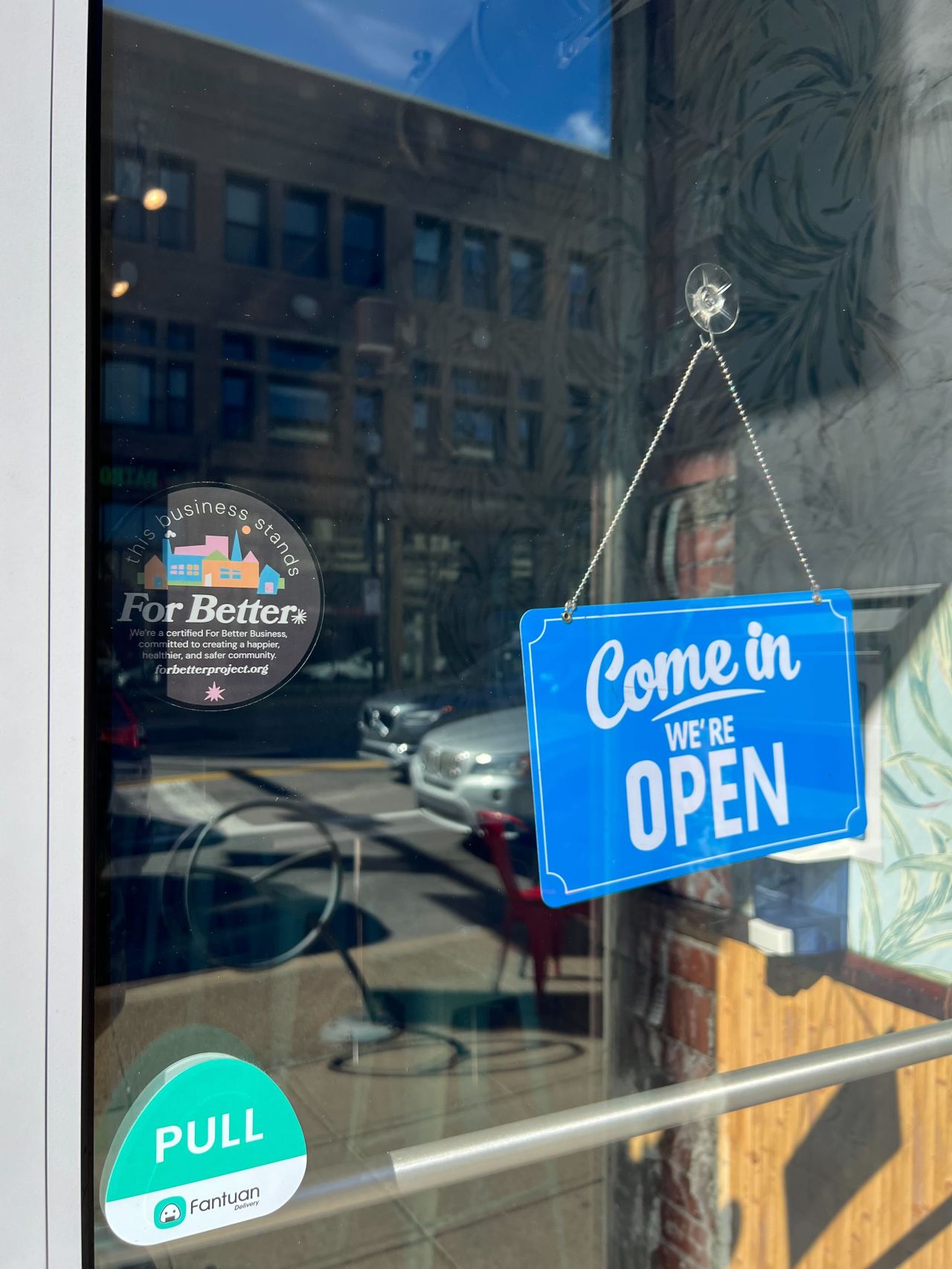 a store front with an open sign and a sticker for the For Better Project